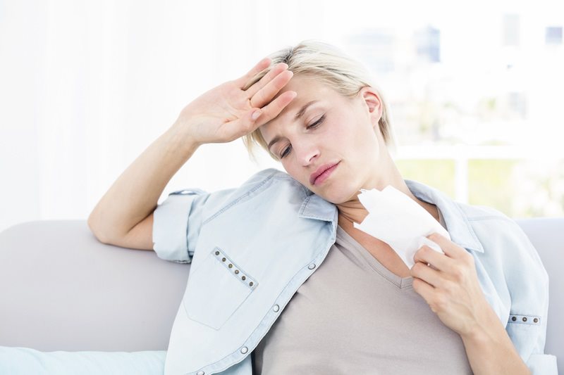 womanholdingatissue Woman holding a tissue with her hand on her head