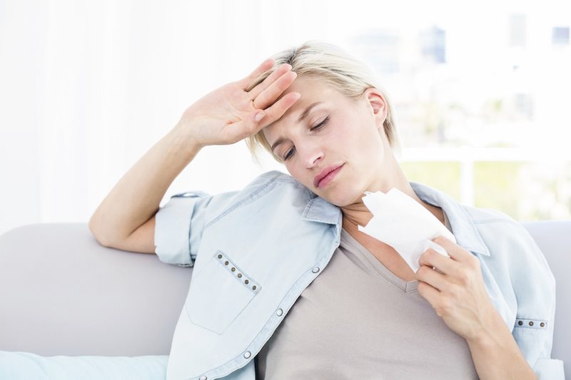 Woman holding a tissue with her hand on her head