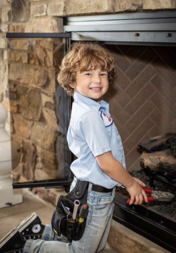 Kohles & Bach kid smiling by a fireplace